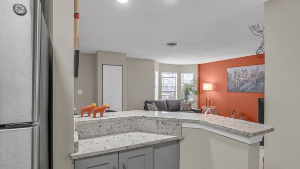 A modern kitchen with a granite countertop, a refrigerator, and a seating area with a sofa and a coffee table. - The Orange Luxe Modern 2bdrm Retreat in Uptown Charlotte ( (Charlotte)
