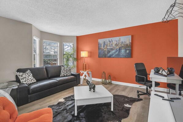 Un salon moderne avec un canapé en cuir noir, une table basse blanche et un tapis noir et blanc.