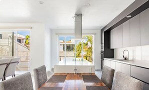 A modern kitchen with a central island, white cabinetry, and a view of the outdoors.