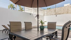 A patio with a table and chairs, a potted plant, and a pool in the background. - Private Pool • 4BR • 5.5 Baths • Secure • Upscale (Zapopan)