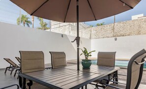 A patio with a table and chairs, a potted plant, and a pool in the background. - Private Pool • 4BR • 5.5 Baths • Secure • Upscale (Zapopan)