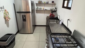 A compact kitchen with a stainless steel refrigerator, a gas stove, and a small window. - Floral Departments (Comunidad)