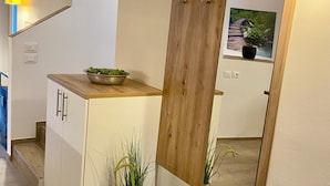 A modern kitchen with a wooden counter, white cabinets, a large mirror, and a potted plant. - Villetta Moscal- „BellaVista“ (Affi)