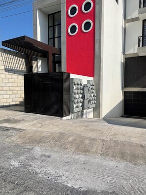 A modern building with a red and white facade, a black gate, and multiple electrical boxes. - MYO boutique loft with parking/Old Quarter (Mexico)