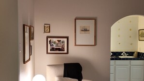 A living room with a rocking chair, a small table with a lamp, and a wall with framed pictures. - Our Coastal Family Home – 2 Blocks to the Beach (Galveston)