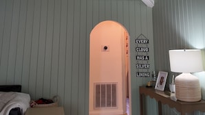 A room with a ceiling fan, a vent, a wall with a sign, a lamp, and a small table with a basket. - Our Coastal Family Home – 2 Blocks to the Beach (Galveston)