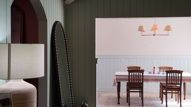 A dining area with a table and chairs, a hanging light fixture, and a large mirror on the wall. - Our Coastal Family Home – 2 Blocks to the Beach (Galveston)
