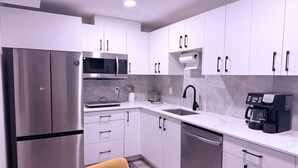 Una cocina moderna con electrodomésticos de acero inoxidable, gabinetes blancos y lavavajillas integrado.