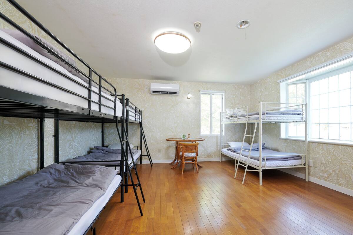 Un dormitorio con literas, una mesita y una ventana.