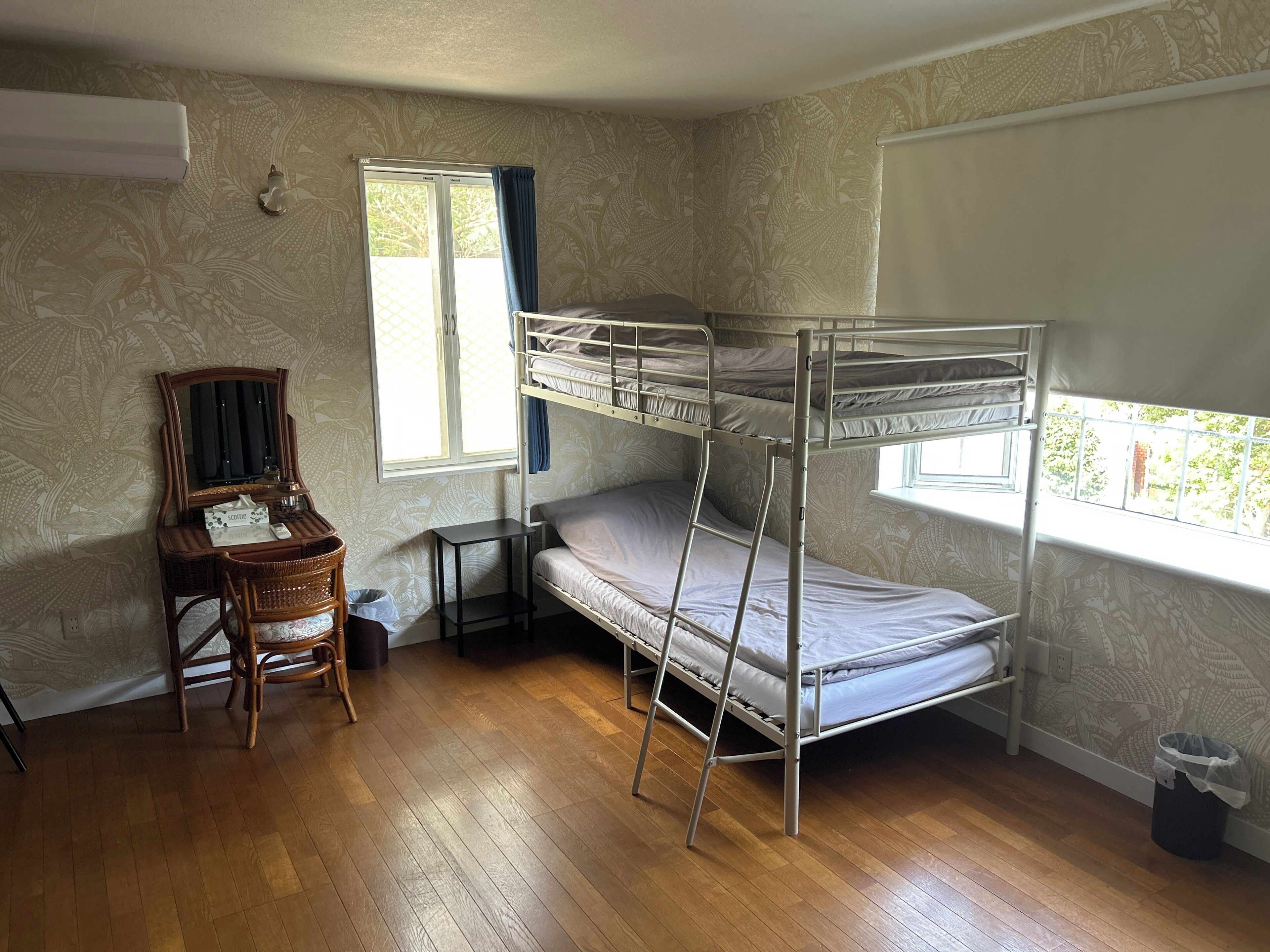 Una habitación con literas, un escritorio con espejo, una silla y un ventanal con cortinas.