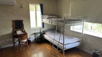 Una habitación con literas, un escritorio con espejo, una silla y un ventanal con cortinas.