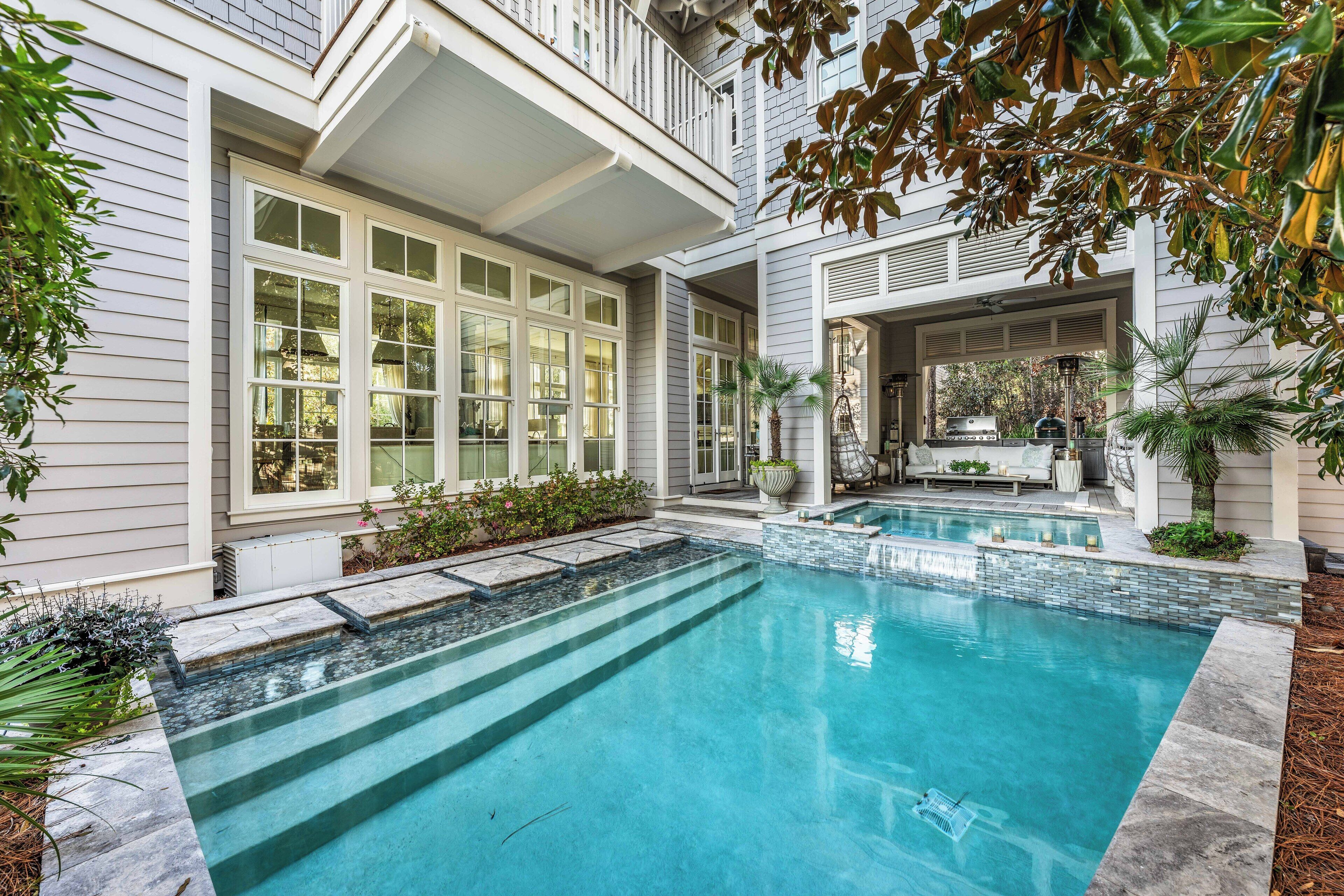 Une maison moderne dotée d’une grande piscine, d’un patio couvert et d’un jardin bien entretenu.