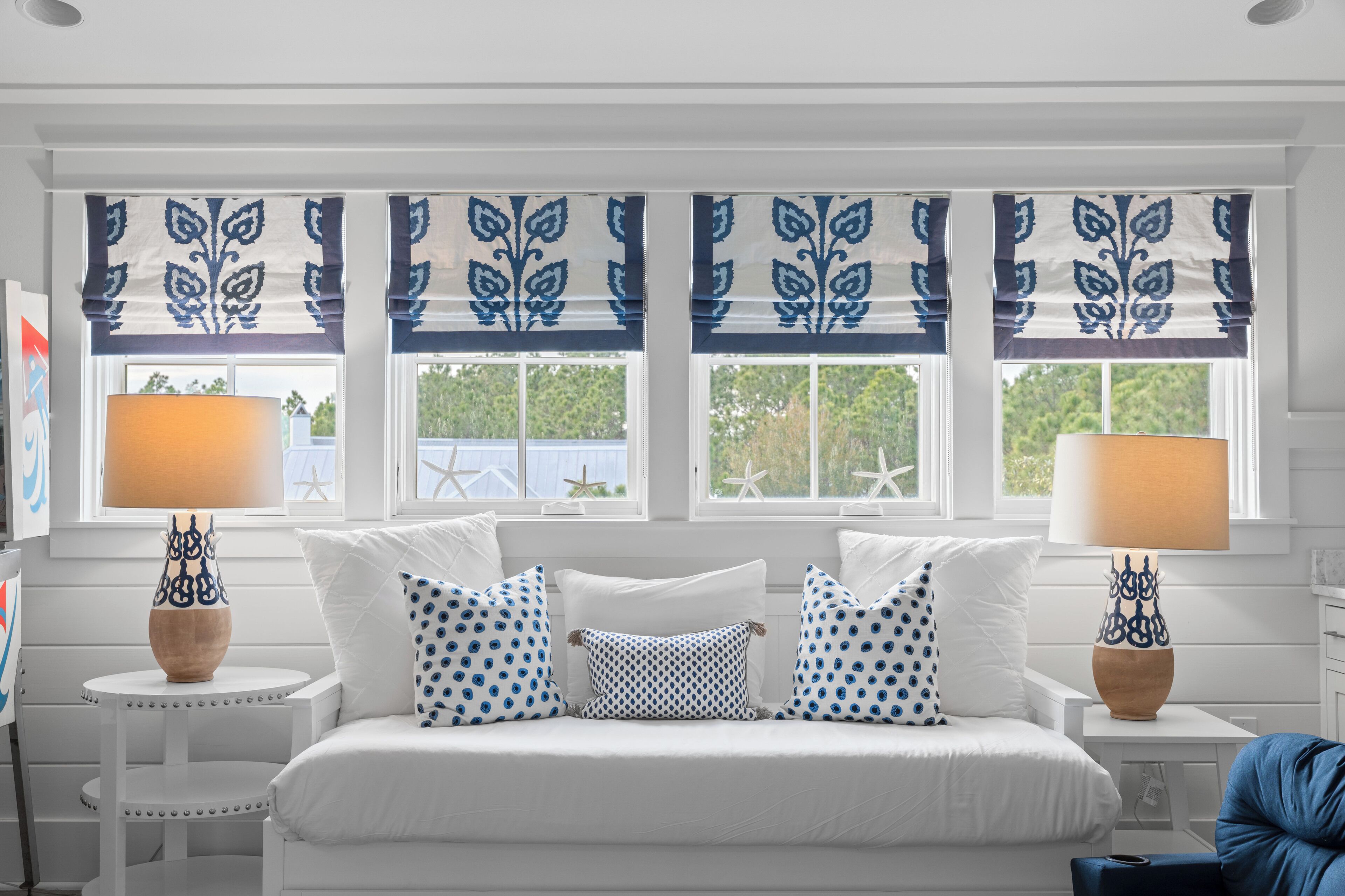 A bedroom with a bed, two bedside tables, and a window with decorative valances.
