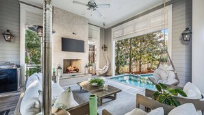 A covered outdoor living area with a pool, seating, and a fireplace. - Camp District Luxury | Private Courtyard Pool | Electric Cart | Beach Club Access (Santa Rosa Beach)