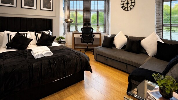 A modern bedroom with a large bed, a desk, a sofa, and a dining table. - Heart of London Signature Stay | Sleeps 6 (Greater London)