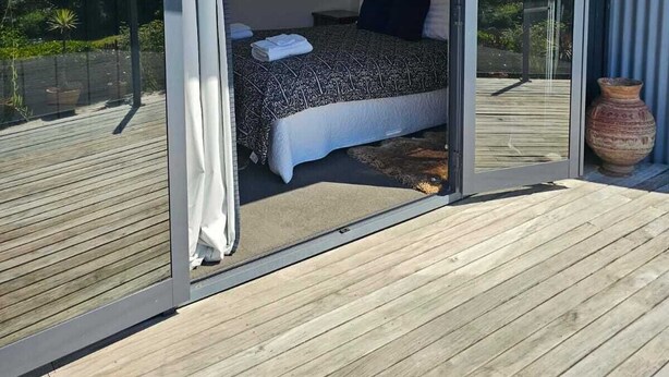 Ein Schlafzimmer mit einer großen Schiebeglasdoor zum Balkon, einem Bett mit gemustertem Überwurf und einem gerahmten Bild an der Wand.