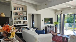 Ein geräumiges Wohnzimmer mit einer Couch, einem Couchtisch, einem Bücherregal und einem Fernseher.
