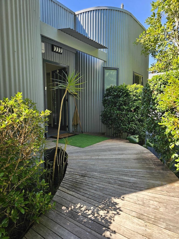 A modern building with a curved facade, a wooden deck, and well-maintained greenery.