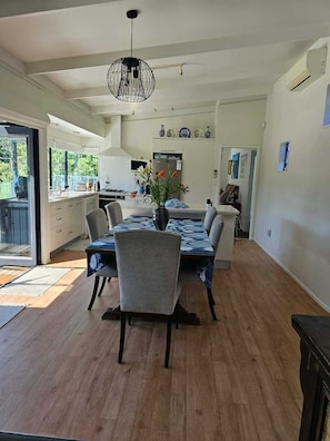 A modern kitchen with a dining area, featuring a large table, chairs, and a hanging light fixture.
