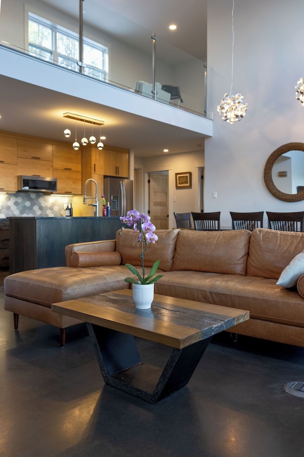 Una sala de estar moderna con un sofá de cuero, una mesa de centro de madera y una orquídea en maceta.