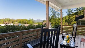 Eine überdachte Terrasse im Freien mit Holzdeck, einem Tisch mit einer Limonadenkanne und einer Bank.
