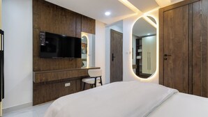 Une chambre à coucher comprenant un lit, un téléviseur, un miroir et des meubles en bois.