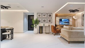 Un salon moderne avec un canapé, une table à manger et des chaises, un téléviseur et des tableaux encadrés accrochés au mur.