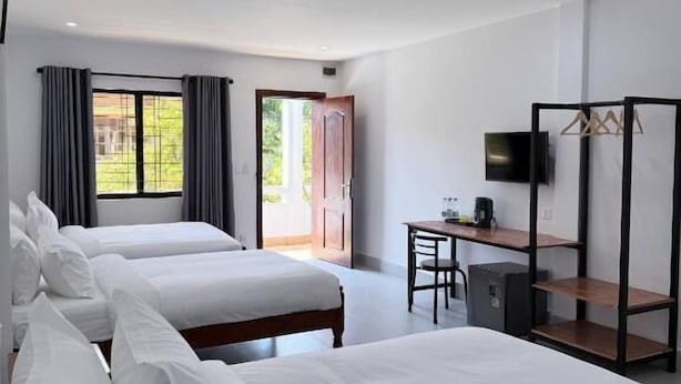 Une chambre d’hôtel avec deux lits, un bureau, une chaise, une télévision et une armoire.