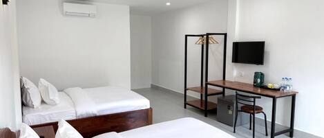 A hotel room with two beds, a desk, a chair, a TV, and a wardrobe.