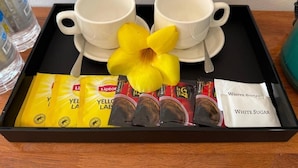 Un plateau avec deux tasses blanches, une fleur jaune et des sachets de thé Lipton et de sucre blanc.