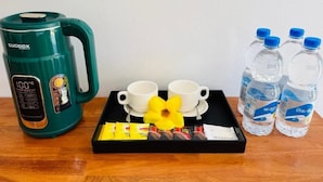 Un plateau avec une tasse, deux verres, une fleur et une boîte de collations.
