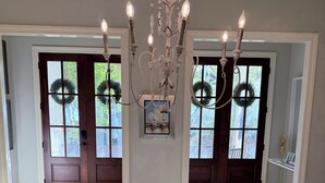 Ein Esszimmer mit Holztisch, weißer Blüten-Dekoration, einer Kronleuchter und zwei Doppeltüren mit Girlanden.