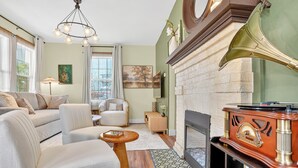 A living room with a fireplace, a gramophone, and a sofa. - Magnolia Soul- Modern Southern Retreat (Macon)