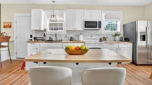 A modern kitchen with white cabinets, a wooden island, and stainless steel appliances. - Magnolia Soul- Modern Southern Retreat (Macon)