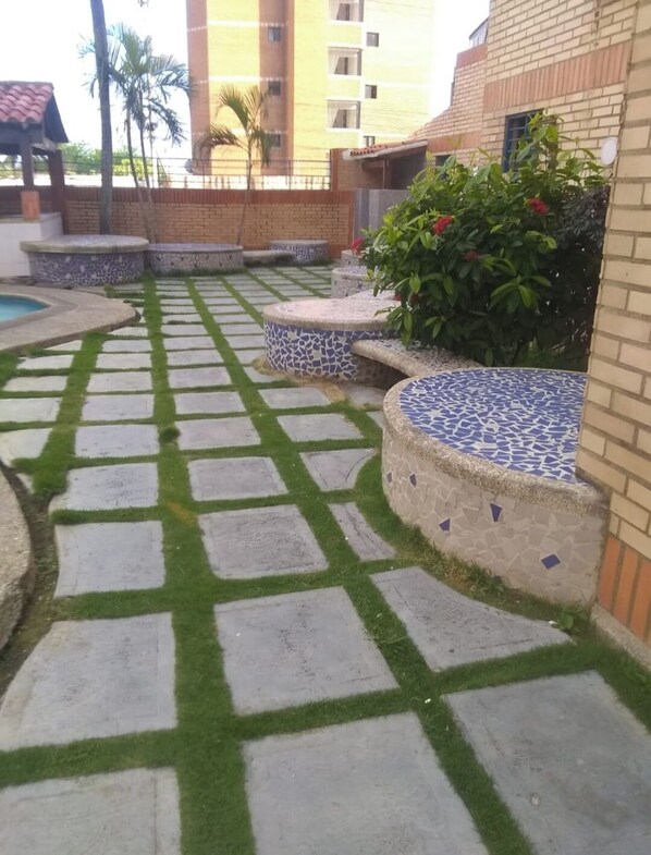 Un patio con baldosas de piedra estampadas, una pequeña piscina y plantas en macetas.