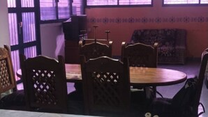 A dining area with a round table and six wooden chairs with lattice backs. There are hanging pendant lights above the table. - Tucacas beach apartment (Tucacas)