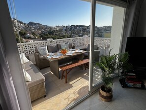 A balcony with a table set for dining, wicker furniture, and a potted plant. - CostaBlancaDreams - Studio 44 in Benissa (Benissa)