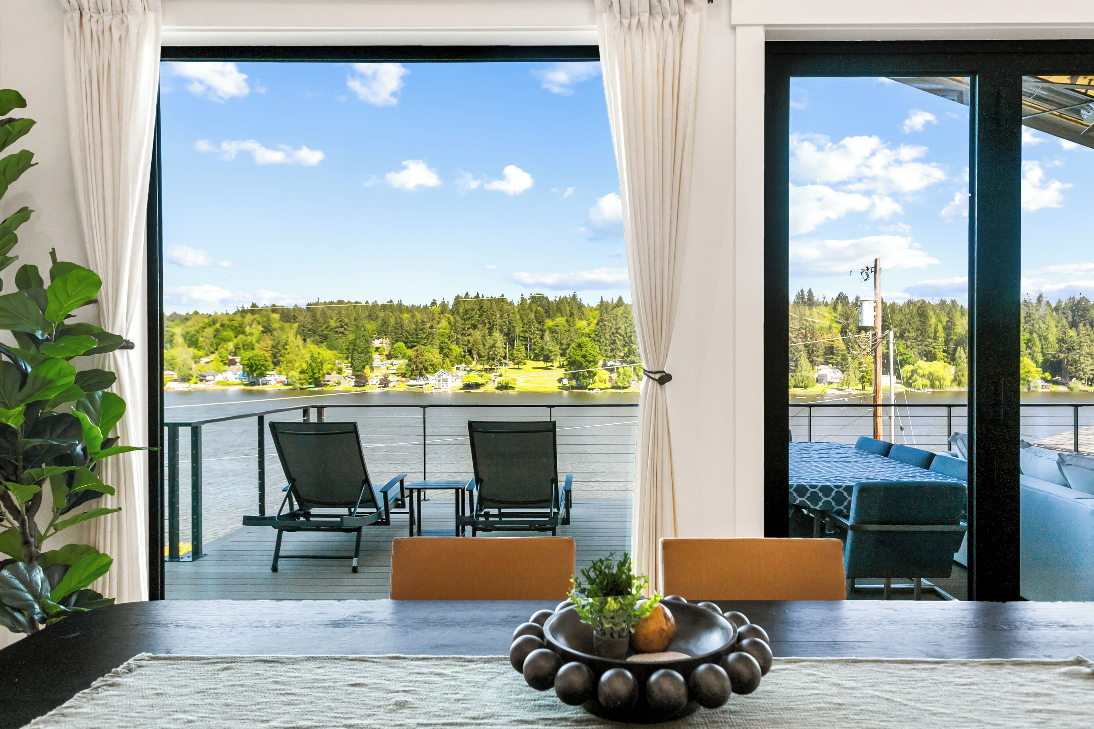 Een balkon met stoelen, een tafel en uitzicht op een bebost gebied.