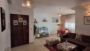 Ein Wohnzimmer mit einer Couch, einem Couchtisch, einem Fernseher und einem Essbereich mit Tisch und Stühlen.