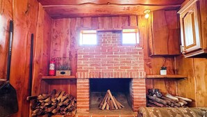Une pièce chaleureuse avec une cheminée en briques, des murs en bois et un canapé.