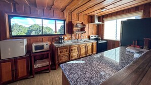 Une cuisine avec des murs en bois, un plan de travail en granit, un réfrigérateur, un four à micro-ondes, une machine à café et une cuisinière.