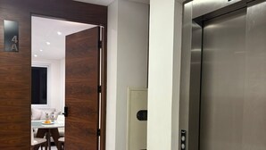Un interior moderno con comedor, una puerta de madera y un ascensor.