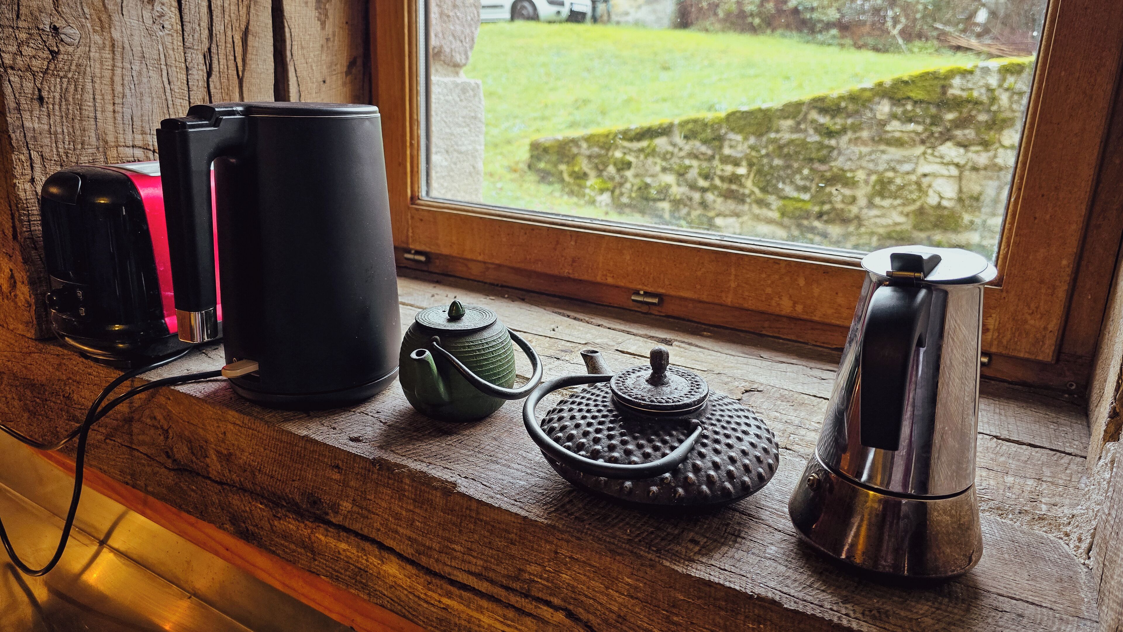 Een houten plank met een koffiezetapparaat, een theepot en een waterkoker.
