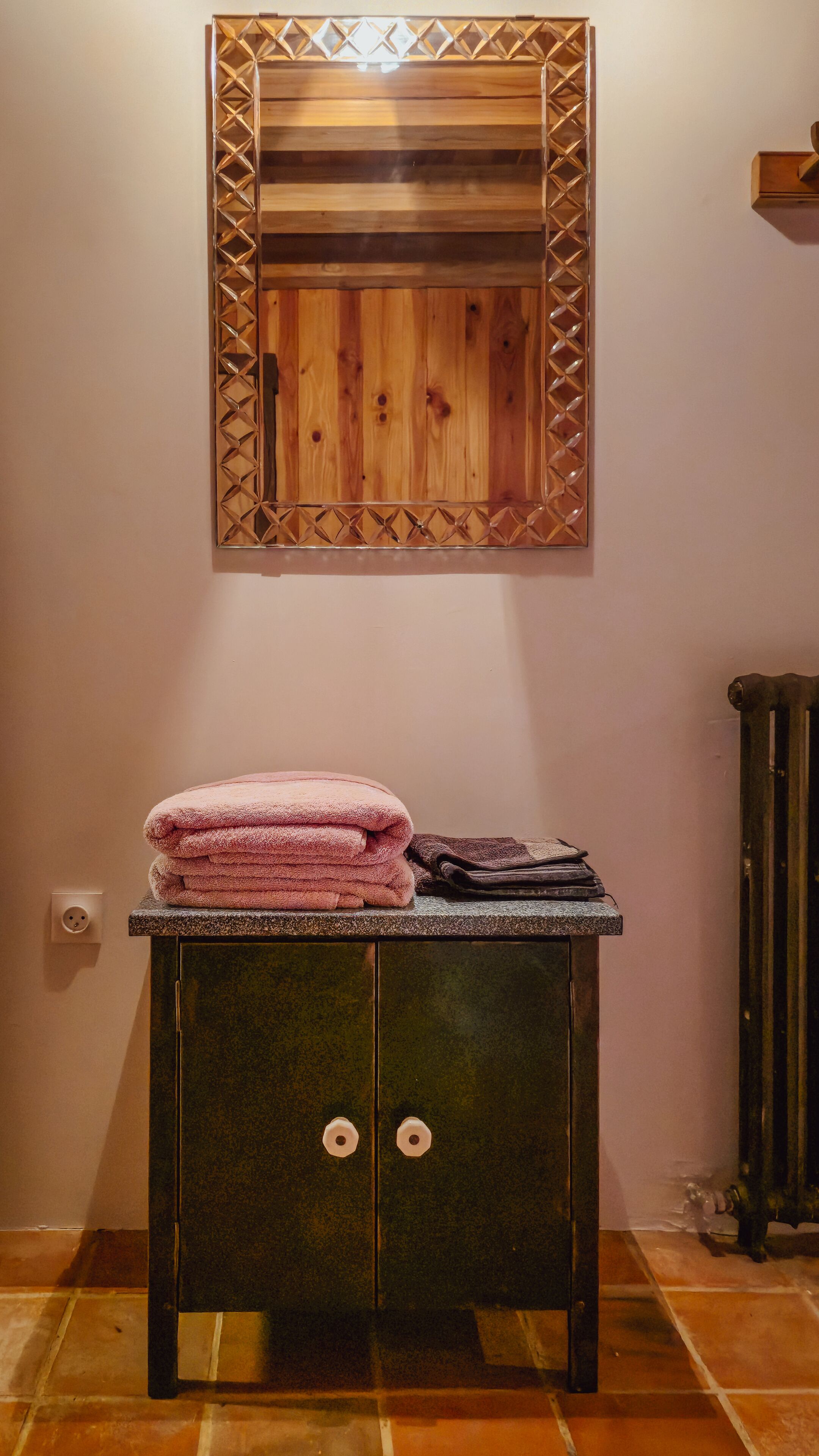 A bathroom with a wooden vanity, a mirror with a geometric frame, and a radiator.