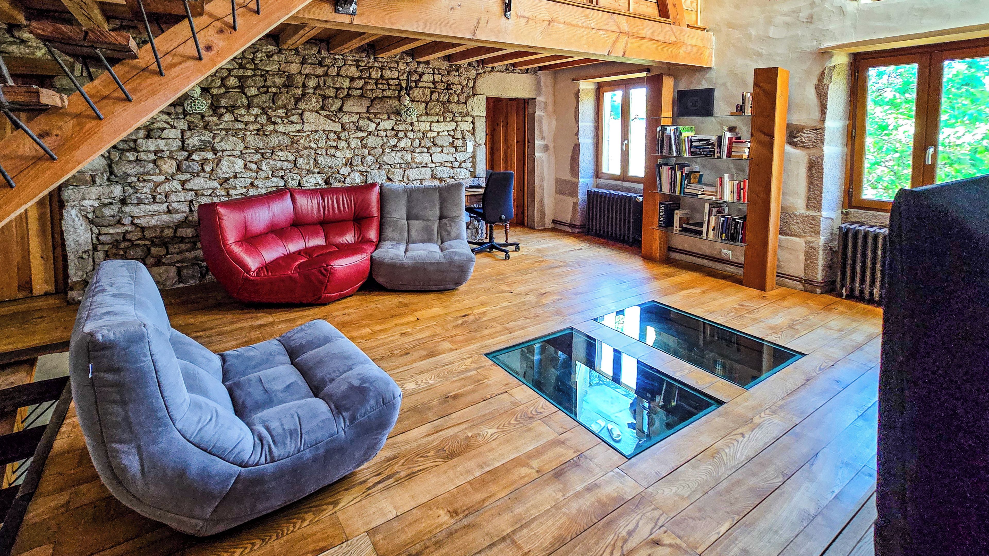 A spacious living area with a stone wall, wooden flooring, and a glass coffee table.