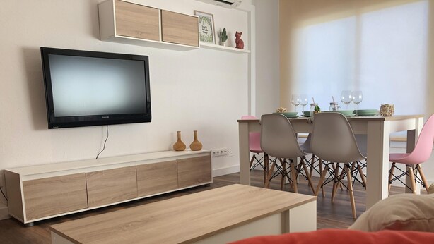 A modern living room with a flat-screen TV, a wooden coffee table, and a dining area with chairs and a table. - AMSTERDAM. Exclusive Comfort on the Costa Brava (Roses)