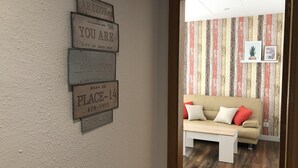 A room with a wooden floor, a beige sofa, and a wall with a striped wallpaper. There are four signs on the wall, each with different text. - AMSTERDAM. Exclusive Comfort on the Costa Brava (Roses)