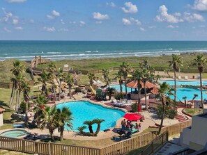 Ein Resort mit großem Pool, Palmen und Blick auf den Ozean.