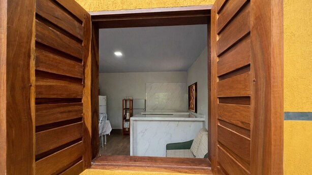 Ein Flur mit Holzhörnern, der zu einem Küchenbereich mit Marmorarbeitsplatte und einem weißen Kühlschrank im Hintergrund führt.