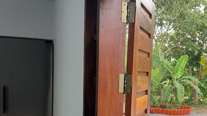 Eine Holztür mit Metallriegel, eine weiße Wand und ein Holzboden.